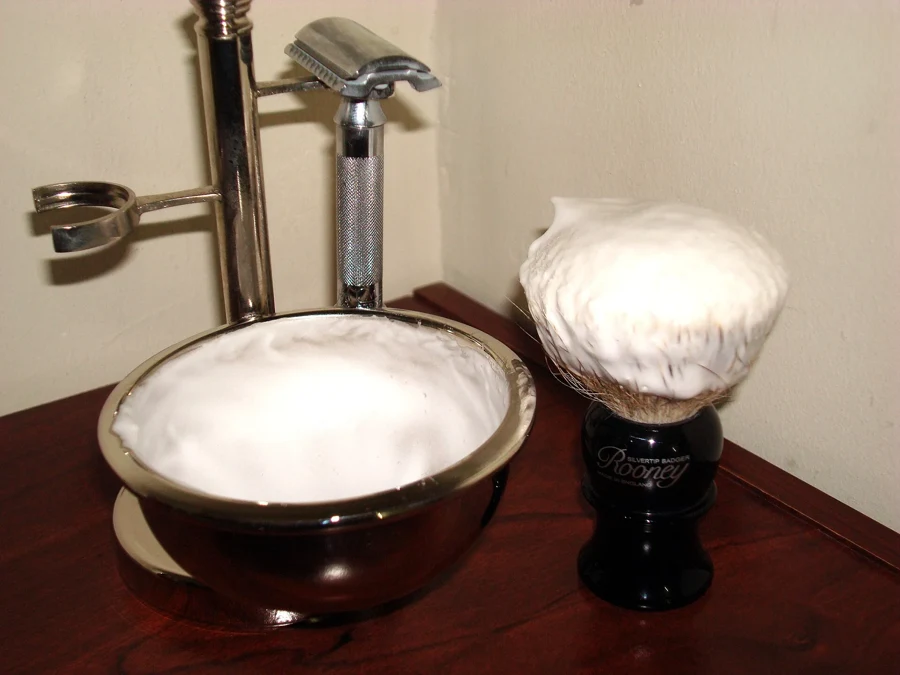 Bol de rasage rempli de mousse, rasoir de sûreté et blaireau chargé de mousse